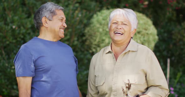 Video of happy biracial senior couple laughing and talking in garden