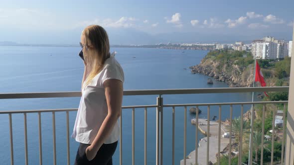 A woman talking to the phone on a hotel balcony against the beautiful scenery