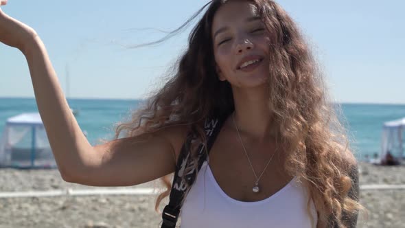 Professional Model in White Top Poses Against Blue Sea