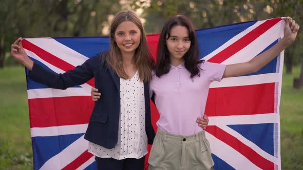 Two Happy Teenage Girls Posing with British Flag in Summer Spring Park Outdoors