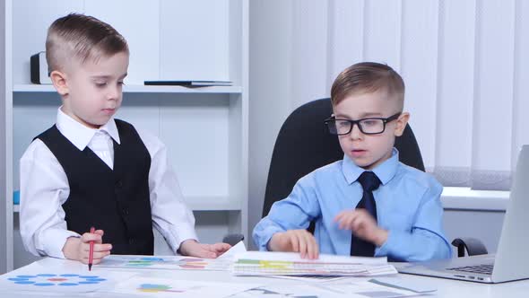 Two Little Boys Businessman in the Office Consider Graphs and Charts