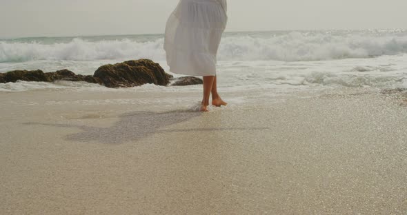 Rear view of African american woman playing with sea water on the beach 4k