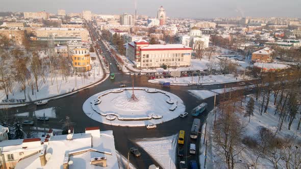 Aerial View of Roundabout Road with Circular Cars in Snow Covered Small European City at Winter