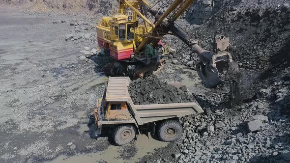 Large Excavator Loading Granite Into Heavy Dump Truck High Angle