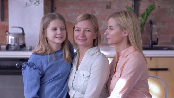 Happy Maternity, Smiling Girls Daughters Kiss Beloved Mother on Cheeks at Same Time Close-up Sitting