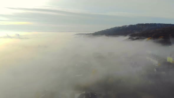 Flying Over the Fabulous Morning Mist Over the City. The Sunrise and the Colored Rays Reflected