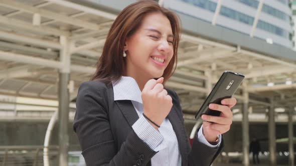 Asian unemployed woman feeling happy after she look at smartphone know the result pass an interview.