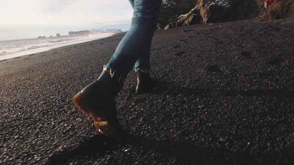 Traveler Woman Walking on Volcanic Black Sand Beach in Iceland