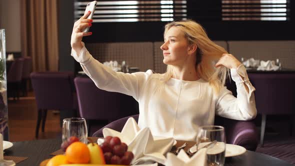 Elegant Woman Sitting at Cafe and Taking Selfie with Her Smart Phone