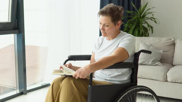 Senior Woman Sitting on the Wheelchair Reading a Book at Home