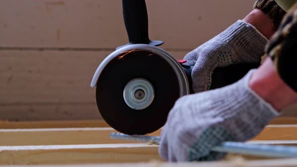 A builder's hands in work gloves cut a metal hairpin with an angle grinder electric tool. Preparatio