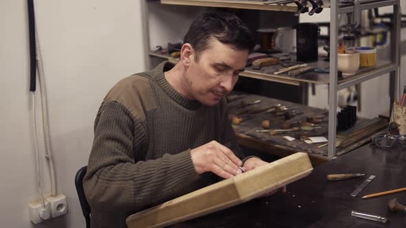 Caucasian Joiner Makes Notches on the Wooden Workpiece with Curved Chisel