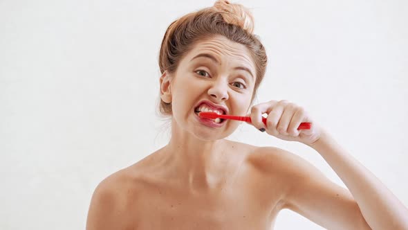 Young Beautiful Naked Girl in Towel Cleaning Teeth Singing with Comb Over White Background