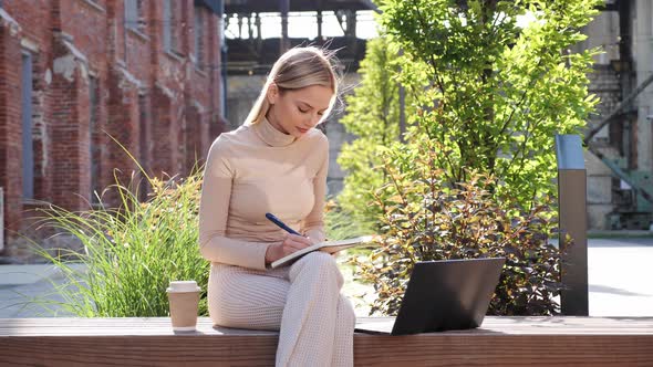 Charming Young Blonde Attractive Girl Freelancer Working with Laptop Outdoor