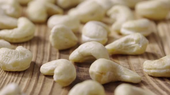 Sliding Shot of Fresh Raw Cashew Nuts Lying on a Textured Wooden Table Surface