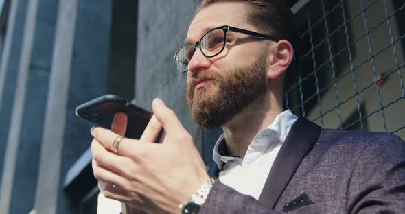 Businessman in Stylish suit in Glasses Talking on Phone with Business Partner and Agrees on meeting