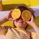 Happy child holding halves of orange fruit like a sunglasses. Slow motion - VideoHive Item for Sale