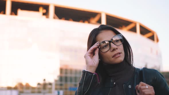 Portrait of Young Stylish Woman in Glasses Outside on Urban Background