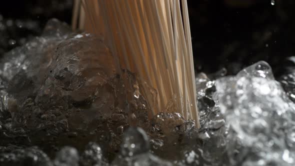 Throwing spaghetti pasta into water. Slow Motion.