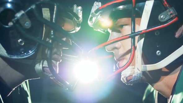 Two American Football Athletes Are Standing Head To Head on a Stadium