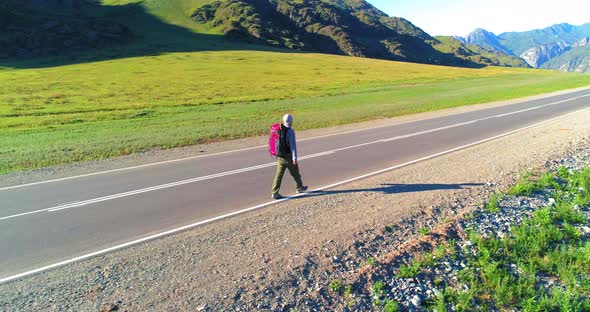 Flight Over Hitchhiker Tourist Walking on Asphalt Road