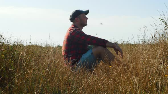 Pensive Lonely Guy In The Field. Young Sad Man Sitting In The Tall Yellow Grass