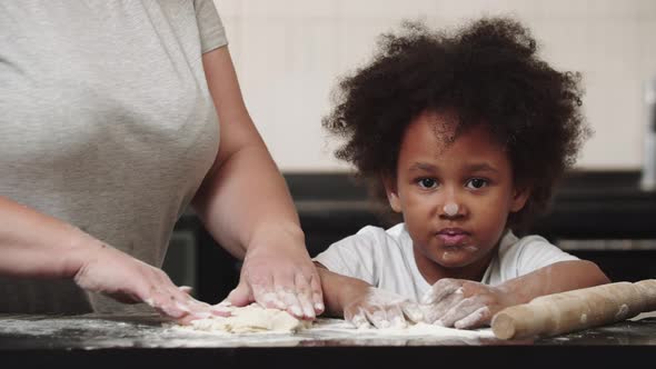 Black Little Smiling Girl with Her White Mother Making Dough