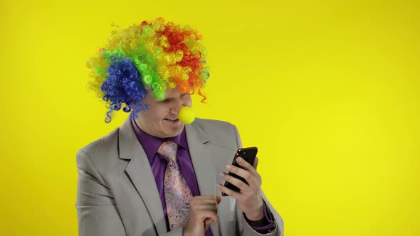 Clown Businessman Entrepreneur in Wig Using App on Smartphone for Online Work