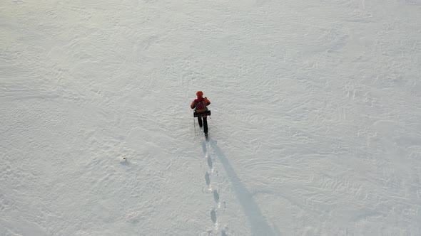 Footage View From Drone  a Lone Traveler with a Backpack Walks Through the Snowy Desert