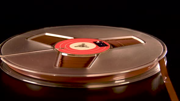 Reel to reel tape rotating before black background