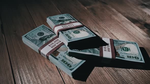 Three Stacks of 10000 American Dollars Banknotes in Bundles Lie on Wooden Table