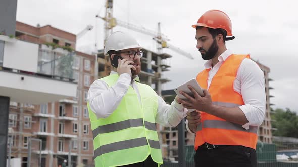 Engineer Speaks on Mobile Phone on Construction Site and Checks the Work of the Worker. Builder