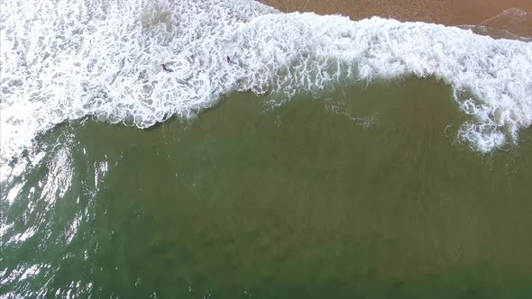 Drone shot of the waves crashing onto the beach