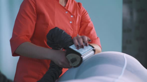 Beautician in Orange Shirt Does Roller Massage to Plump Lady