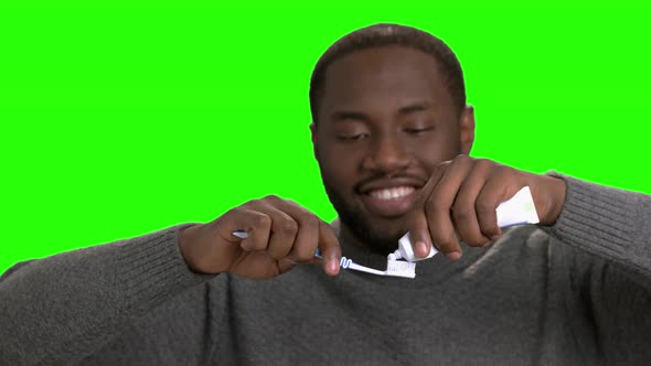 Afro American Guy Putting Toothpaste on His Toothbrush.