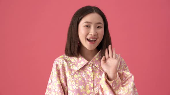 Cheerful Asian woman doing hello gesture at the camera