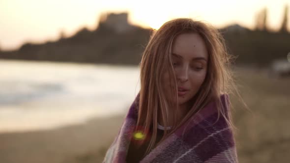 Portrait of a Girl Wrapped in a Blanket on the Beach in Autumn