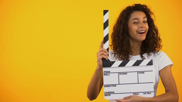 Beautiful Mixed-Race Woman Winking and Holding Clapper Board, Movie Shooting