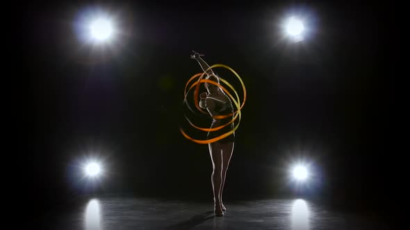 Flexible Gymnast with Tape Creates Beautiful Hands Graceful movements.Black Background. Light Rear
