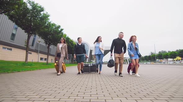 Five Traveling Friends Returning From a Trip in the Background of the Airport with Luggage in Hand