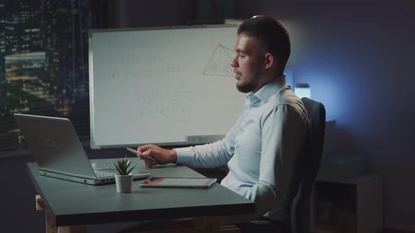 Multiethnic Young Businessman Providing Video Call on Computer and Showing Something on Whiteboard