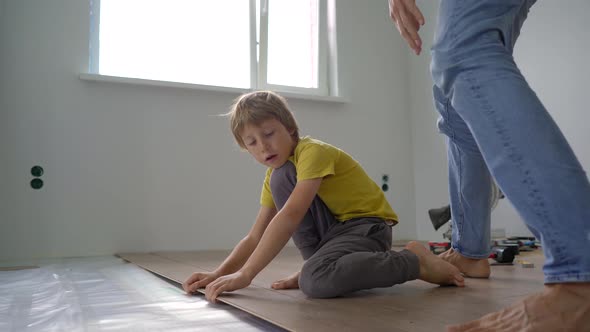 Father and His Little Son Install Laminate on the Floor in Their Apartment