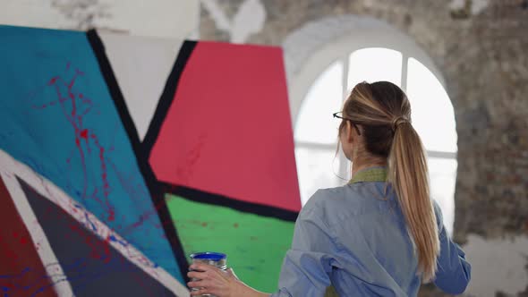 Woman Uses Wide Brush and Color Paints Splashing Gesture on Canvas