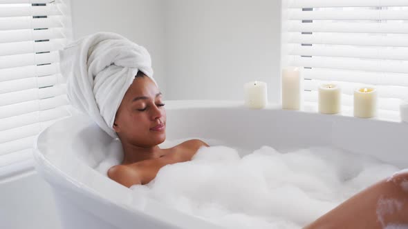 African american woman relaxing in the bath tub in the bathroom at home