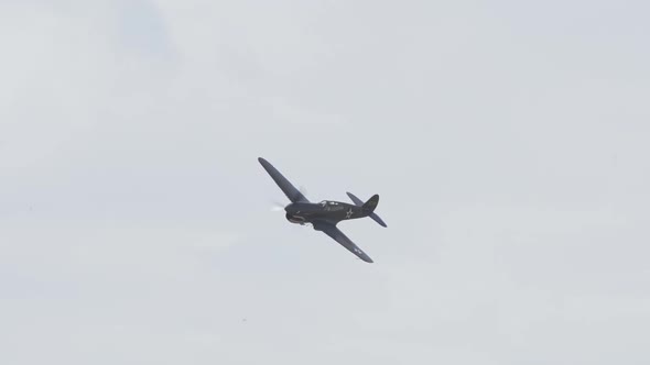 Slow motion of a P-40 Warhawk performing maneuvers during an air show.