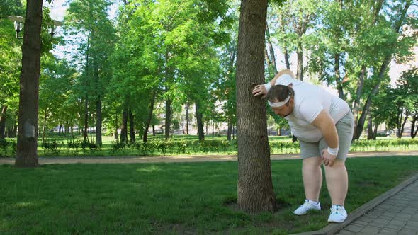 Fat Man Tired After Running in Park, Leaning on Tree, Tiresome Workouts Outdoors