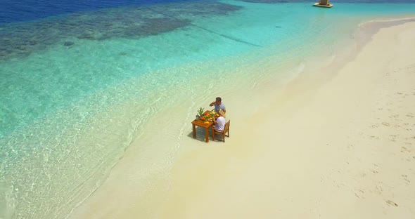 Aerial drone view of a man and woman eating breakfast on a tropical island beach