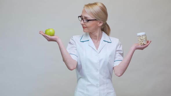 Nutritionist Doctor Healthy Lifestyle Concept - Holding Organic Green Apple and Jar of Vitamin Pills