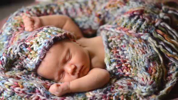 Newborn Baby Sleeps in a Knitted Scarf