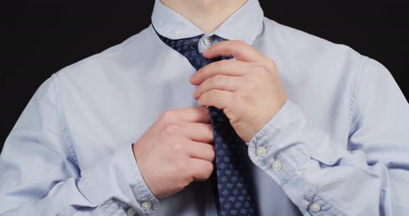 Close up of a man's hands adjusting his tie